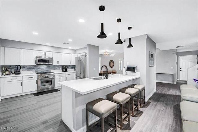 8316 Maplestar Rd, Las Vegas, NV 89128 - kitchen featuring premium appliances, a sink, a kitchen bar, a peninsula, and baseboards