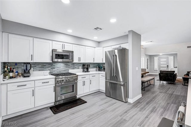 8316 Maplestar Rd, Las Vegas, NV 89128 - kitchen with high end appliances, light countertops, backsplash, white cabinets, and light wood-style floors