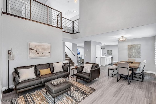 8316 Maplestar Rd, Las Vegas, NV 89128 - living room with stairway, wood finished floors, baseboards, a towering ceiling, and a chandelier
