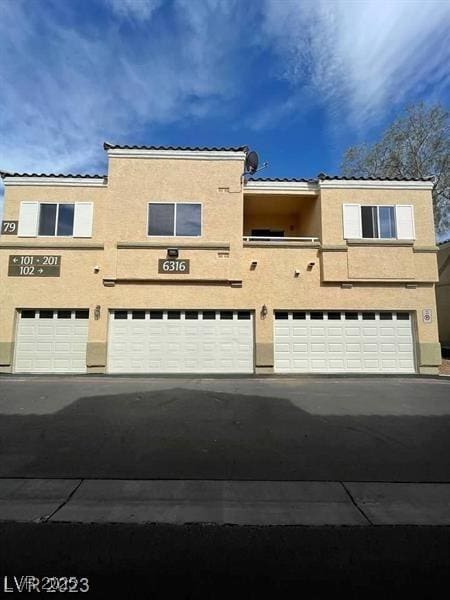 6316 Beige Bluff St Unit 201, North Las Vegas, NV 89081 - view of front of house with a garage, a tiled roof, stucco siding, and driveway