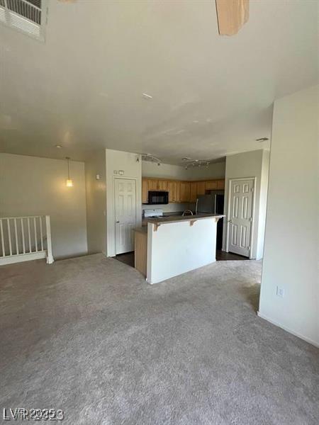 6316 Beige Bluff St Unit 201, North Las Vegas, NV 89081 - kitchen featuring black microwave, open floor plan, fridge, brown cabinetry, and dark carpet