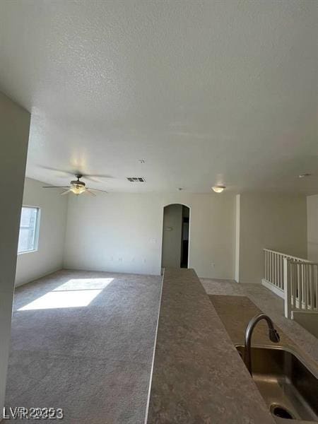 6316 Beige Bluff St Unit 201, North Las Vegas, NV 89081 - living area with arched walkways, a ceiling fan, carpet floors, and a textured ceiling