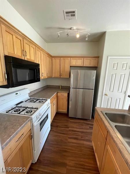 6316 Beige Bluff St Unit 201, North Las Vegas, NV 89081 - kitchen with black microwave, white gas stove, freestanding refrigerator, a sink, and dark wood-type flooring
