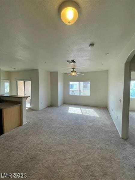 6316 Beige Bluff St Unit 201, North Las Vegas, NV 89081 - unfurnished living room with arched walkways, light colored carpet, and a ceiling fan