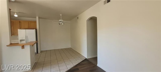 75 N Valle Verde Dr Unit 2121, Henderson, NV 89074 - kitchen with arched walkways, white refrigerator with ice dispenser, ceiling fan, and light tile patterned flooring