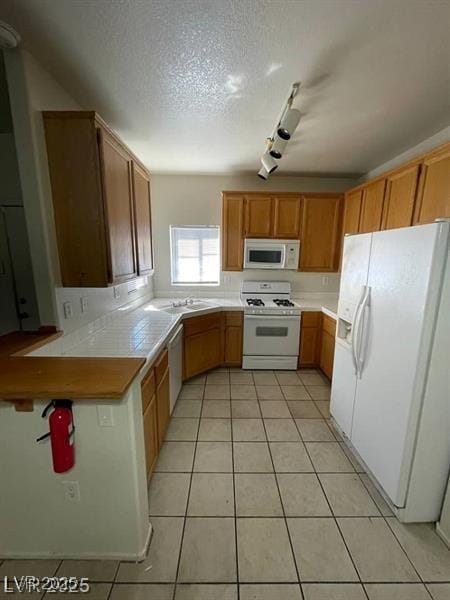 75 N Valle Verde Dr Unit 2121, Henderson, NV 89074 - kitchen featuring white appliances, light tile patterned floors, track lighting, a textured ceiling, and tile counters