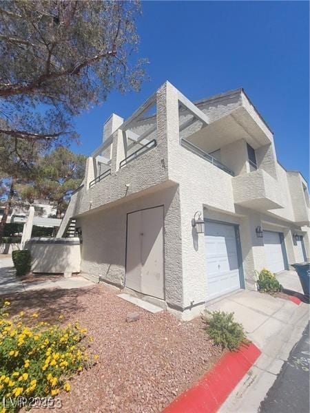 2761 Lodestone Dr Unit 63, Las Vegas, NV 89117 - view of home's exterior featuring stucco siding, concrete driveway, a garage, a chimney, and stairway