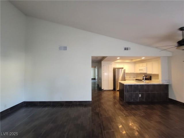 2761 Lodestone Dr Unit 63, Las Vegas, NV 89117 - kitchen with freestanding refrigerator, a peninsula, vaulted ceiling, white cabinetry, and dark wood-style flooring