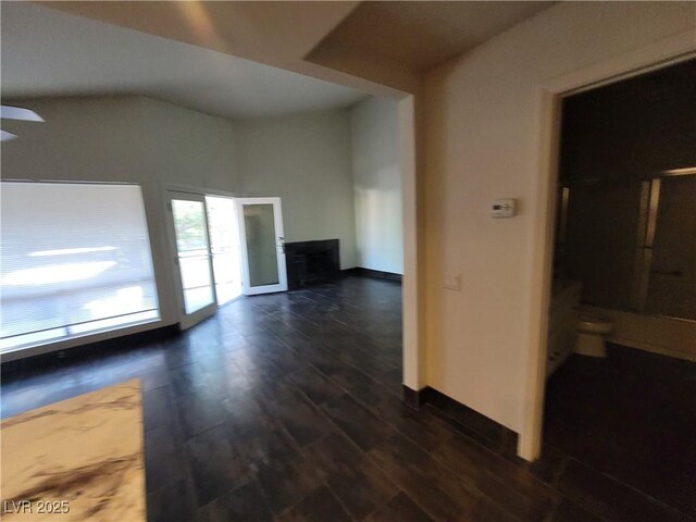 2761 Lodestone Dr Unit 63, Las Vegas, NV 89117 - unfurnished living room with dark wood finished floors, baseboards, ceiling fan, and vaulted ceiling