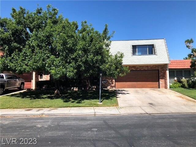 3797 Monument St, Las Vegas, NV 89121 - view of front of property featuring a garage, driveway, brick siding, and a front lawn