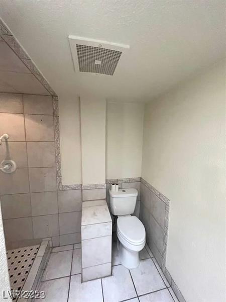 3797 Monument St, Las Vegas, NV 89121 - full bathroom featuring a stall shower, tile walls, toilet, wainscoting, and tile patterned flooring