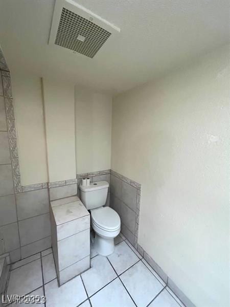 3797 Monument St, Las Vegas, NV 89121 - bathroom with tile walls, toilet, a wainscoted wall, and tile patterned flooring