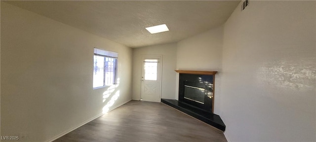 1301 Madison Ave, Las Vegas, NV 89106 - unfurnished living room featuring vaulted ceiling, dark wood-type flooring, a textured ceiling, baseboards, and a glass covered fireplace