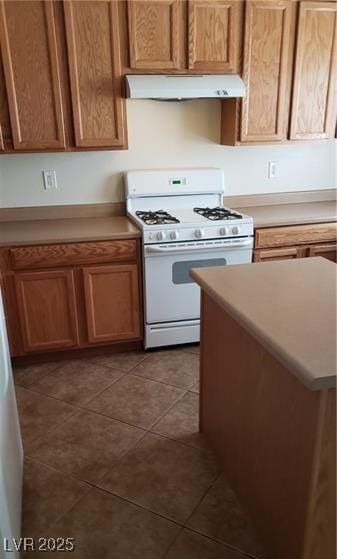 8749 Brilliant Star Dr, Las Vegas, NV 89178 - kitchen featuring white range with gas cooktop, under cabinet range hood, light countertops, and tile patterned floors