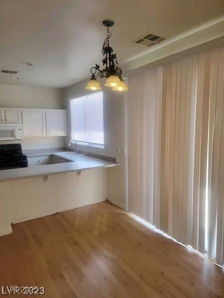8149 Palace Monaco Ave, Las Vegas, NV 89117 - kitchen featuring white microwave, range, light wood finished floors, and hanging light fixtures