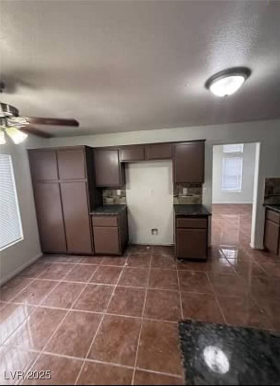 5115 Blossom Ave, Las Vegas, NV 89142 - kitchen with dark countertops, a ceiling fan, dark tile patterned floors, and tasteful backsplash