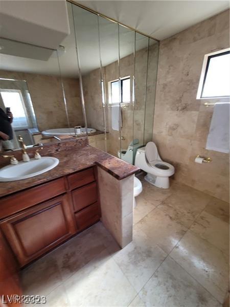 3480 E Hacienda Ave, Las Vegas, NV 89120 - full bath featuring vanity, toilet, a stall shower, tile patterned flooring, and tile walls