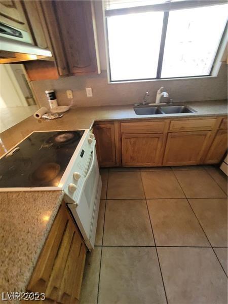 3480 E Hacienda Ave, Las Vegas, NV 89120 - kitchen featuring a sink, light tile patterned floors, light countertops, under cabinet range hood, and brown cabinetry