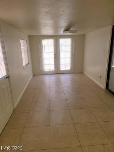 3480 E Hacienda Ave, Las Vegas, NV 89120 - spare room featuring light tile patterned floors, baseboards, a textured ceiling, and french doors