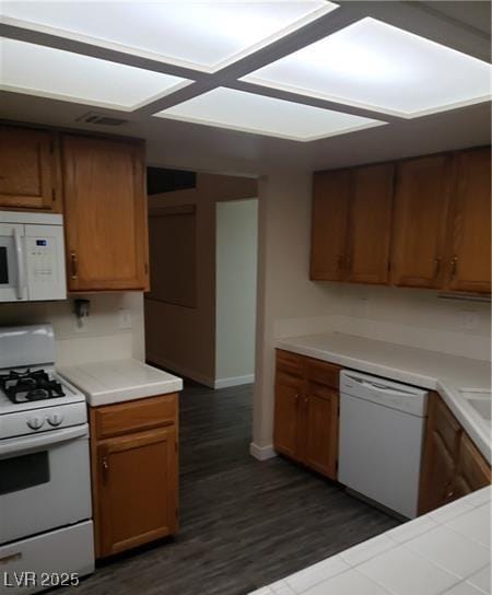 2720 Knightsbridge Rd, Henderson, NV 89074 - kitchen with white appliances, light countertops, dark wood finished floors, and brown cabinets
