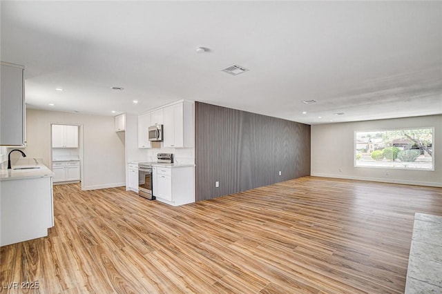 3386 El Camino Real, Las Vegas, NV 89121 - unfurnished living room featuring light wood finished floors, recessed lighting, a sink, and baseboards