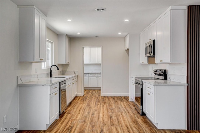 3386 El Camino Real, Las Vegas, NV 89121 - kitchen featuring appliances with stainless steel finishes, a sink, light wood finished floors, white cabinetry, and light stone counters
