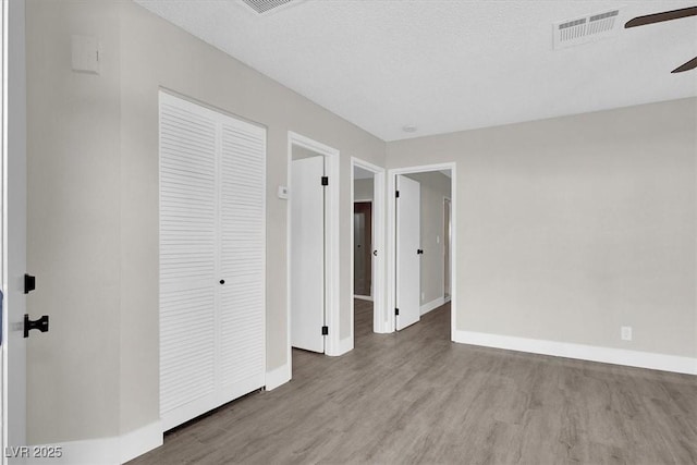 417 N Lamb Blvd Unit E, Las Vegas, NV 89110 - unfurnished bedroom featuring wood finished floors, baseboards, a closet, a ceiling fan, and a textured ceiling