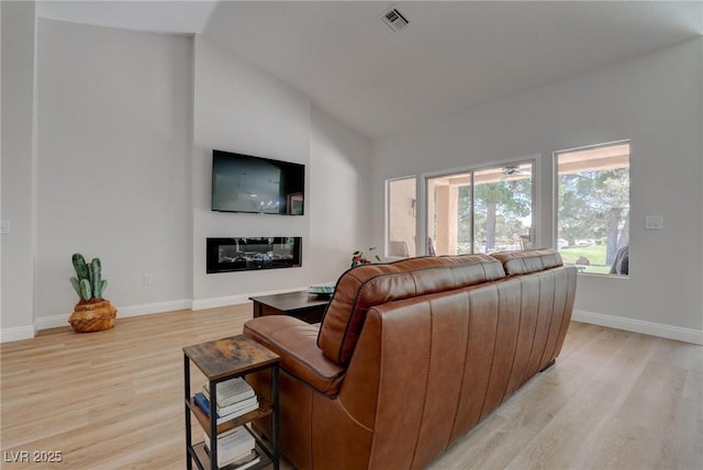 3040 Hidden Treasure Dr, Las Vegas, NV 89134 - living area with light wood finished floors, baseboards, a glass covered fireplace, and vaulted ceiling