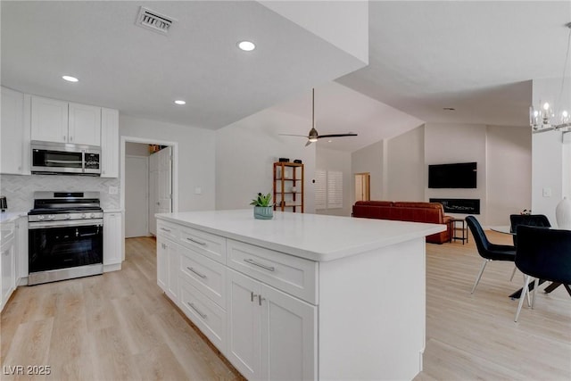 3040 Hidden Treasure Dr, Las Vegas, NV 89134 - kitchen featuring stainless steel appliances, light wood-style floors, white cabinetry, lofted ceiling, and light countertops