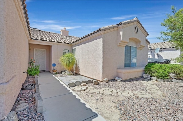 6125 Desert Haven Rd, Las Vegas, NV 89130 - view of side of home featuring a tiled roof, stucco siding, and a chimney