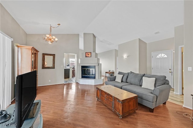 6125 Desert Haven Rd, Las Vegas, NV 89130 - living area featuring a chandelier, wood finished floors, a glass covered fireplace, baseboards, and vaulted ceiling