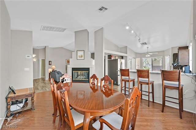 6125 Desert Haven Rd, Las Vegas, NV 89130 - dining area with vaulted ceiling, light wood finished floors, a ceiling fan, a glass covered fireplace, and rail lighting