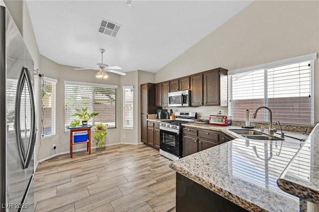 6125 Desert Haven Rd, Las Vegas, NV 89130 - kitchen with stainless steel appliances, a sink, dark brown cabinets, light stone countertops, and lofted ceiling