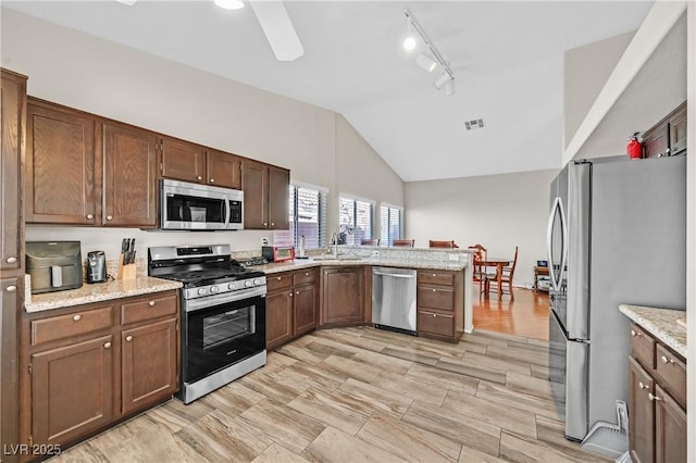 6125 Desert Haven Rd, Las Vegas, NV 89130 - kitchen with appliances with stainless steel finishes, vaulted ceiling, a peninsula, a sink, and light stone countertops