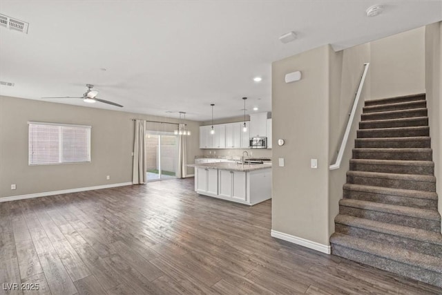 7051 Denio Island St, North Las Vegas, NV 89084 - kitchen with stainless steel microwave, open floor plan, white cabinetry, baseboards, and dark wood-type flooring
