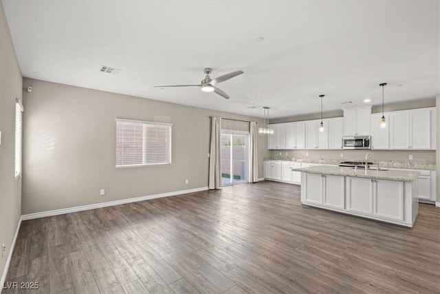 7051 Denio Island St, North Las Vegas, NV 89084 - kitchen with stainless steel microwave, open floor plan, white cabinets, and dark wood-type flooring