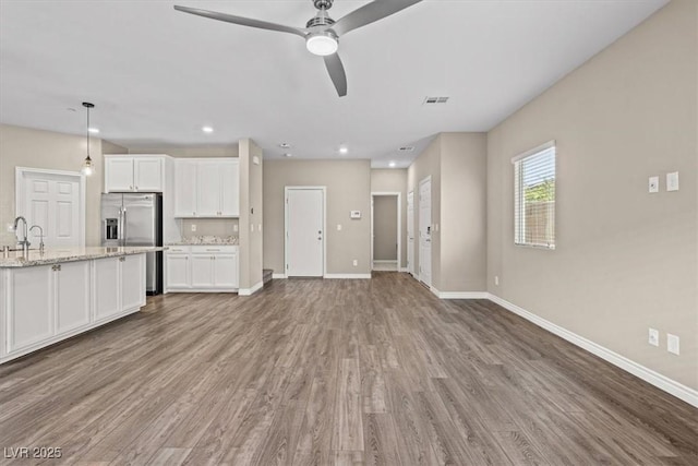 7051 Denio Island St, North Las Vegas, NV 89084 - kitchen with wood finished floors, white cabinets, stainless steel fridge, baseboards, and recessed lighting