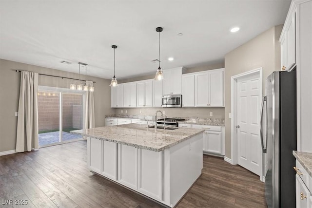 7051 Denio Island St, North Las Vegas, NV 89084 - kitchen featuring stainless steel appliances, dark wood-style flooring, white cabinetry, an island with sink, and recessed lighting