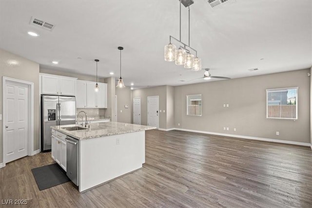 7051 Denio Island St, North Las Vegas, NV 89084 - kitchen featuring stainless steel appliances, ceiling fan, white cabinets, a sink, and an island with sink