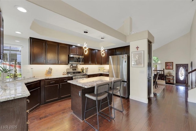 8224 Fawn Meadow Ave, Las Vegas, NV 89149 - kitchen with appliances with stainless steel finishes, dark brown cabinetry, light stone counters, a center island, and vaulted ceiling
