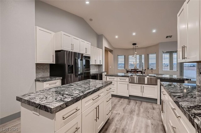 4740 W Agate Ave, Las Vegas, NV 89139 - kitchen featuring a sink, black refrigerator with ice dispenser, vaulted ceiling, backsplash, and light wood-type flooring