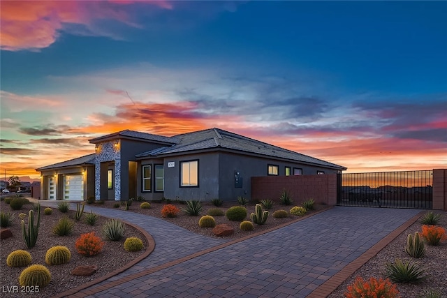 4740 W Agate Ave, Las Vegas, NV 89139 - property exterior at dusk with a gate, curved driveway, stucco siding, and a garage