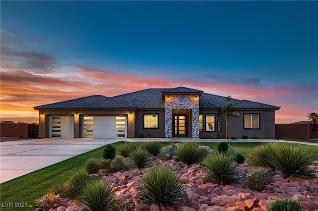 4740 W Agate Ave, Las Vegas, NV 89139 - prairie-style house with an attached garage, driveway, stone siding, and stucco siding