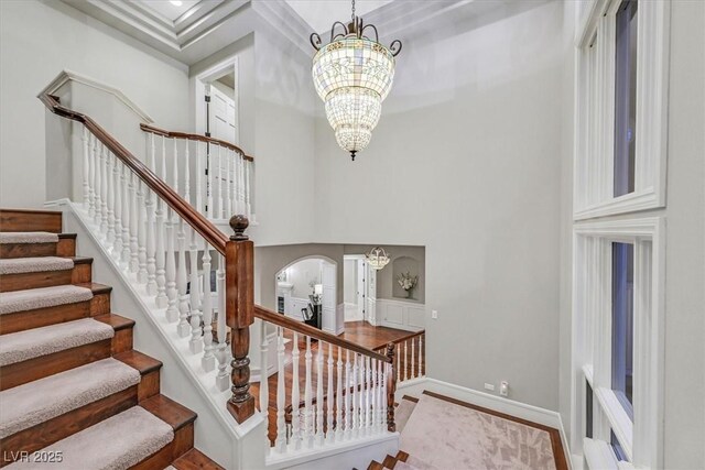 1809 White Hawk Ct, Las Vegas, NV 89134 - staircase with arched walkways, a high ceiling, a chandelier, and baseboards