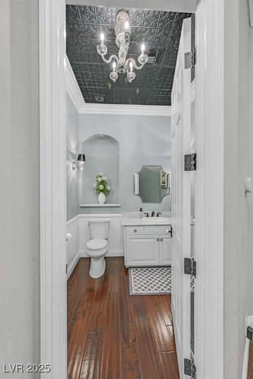 1809 White Hawk Ct, Las Vegas, NV 89134 - bathroom featuring toilet, hardwood / wood-style flooring, vanity, a chandelier, and an ornate ceiling