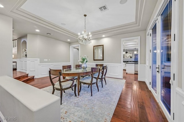 1809 White Hawk Ct, Las Vegas, NV 89134 - dining space featuring a raised ceiling, dark wood-type flooring, a decorative wall, a chandelier, and wainscoting