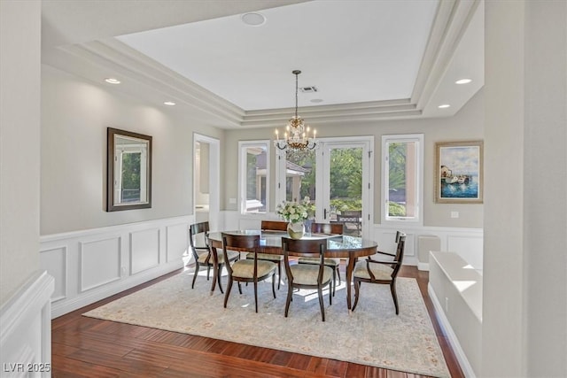 1809 White Hawk Ct, Las Vegas, NV 89134 - dining space with a chandelier, a decorative wall, a tray ceiling, dark wood-style flooring, and wainscoting