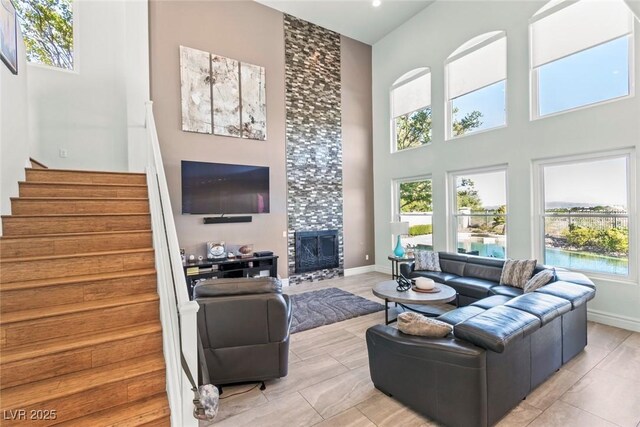 9301 Queen Charlotte Dr, Las Vegas, NV 89145 - living area with healthy amount of natural light, a high ceiling, stairway, and a tiled fireplace