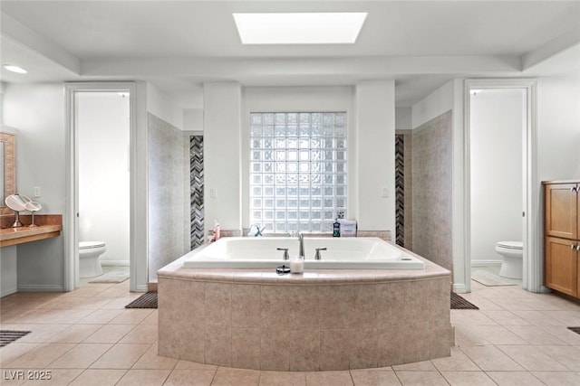9301 Queen Charlotte Dr, Las Vegas, NV 89145 - bathroom featuring toilet, a garden tub, tile patterned flooring, a skylight, and baseboards