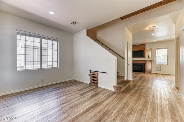 7900 Dutch Canyon Ct, Las Vegas, NV 89131 - unfurnished living room with stairway, a glass covered fireplace, light wood-type flooring, and recessed lighting